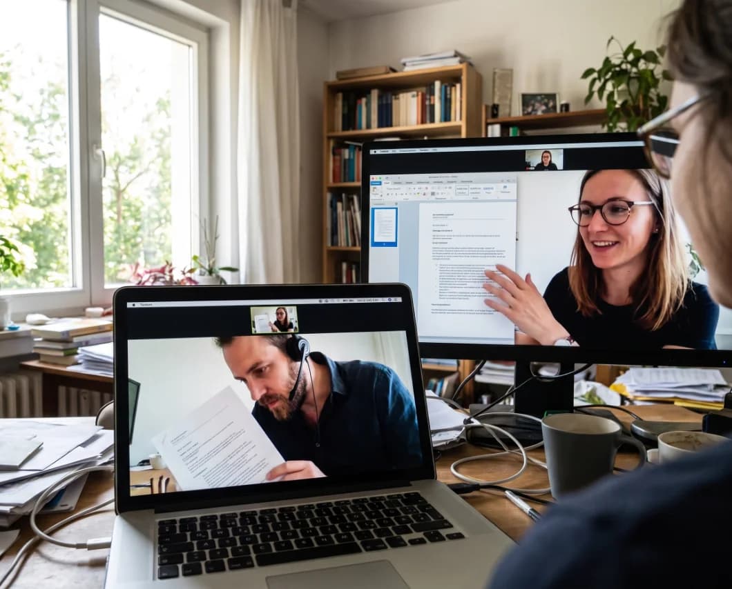 Two people on a video call reviewing work together, one screen with a document open.